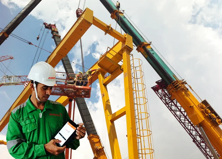 Jenmon employee using the eSOS system on a tablet, with cranes visible in the background.